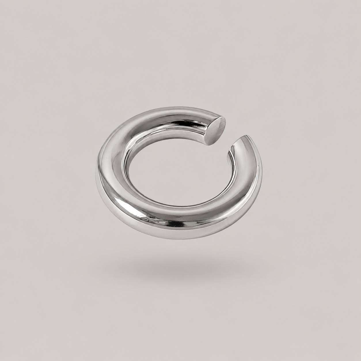 A polished silver-toned metal hoop cuff with a flat, open circular design, shown floating against a solid light gray background.