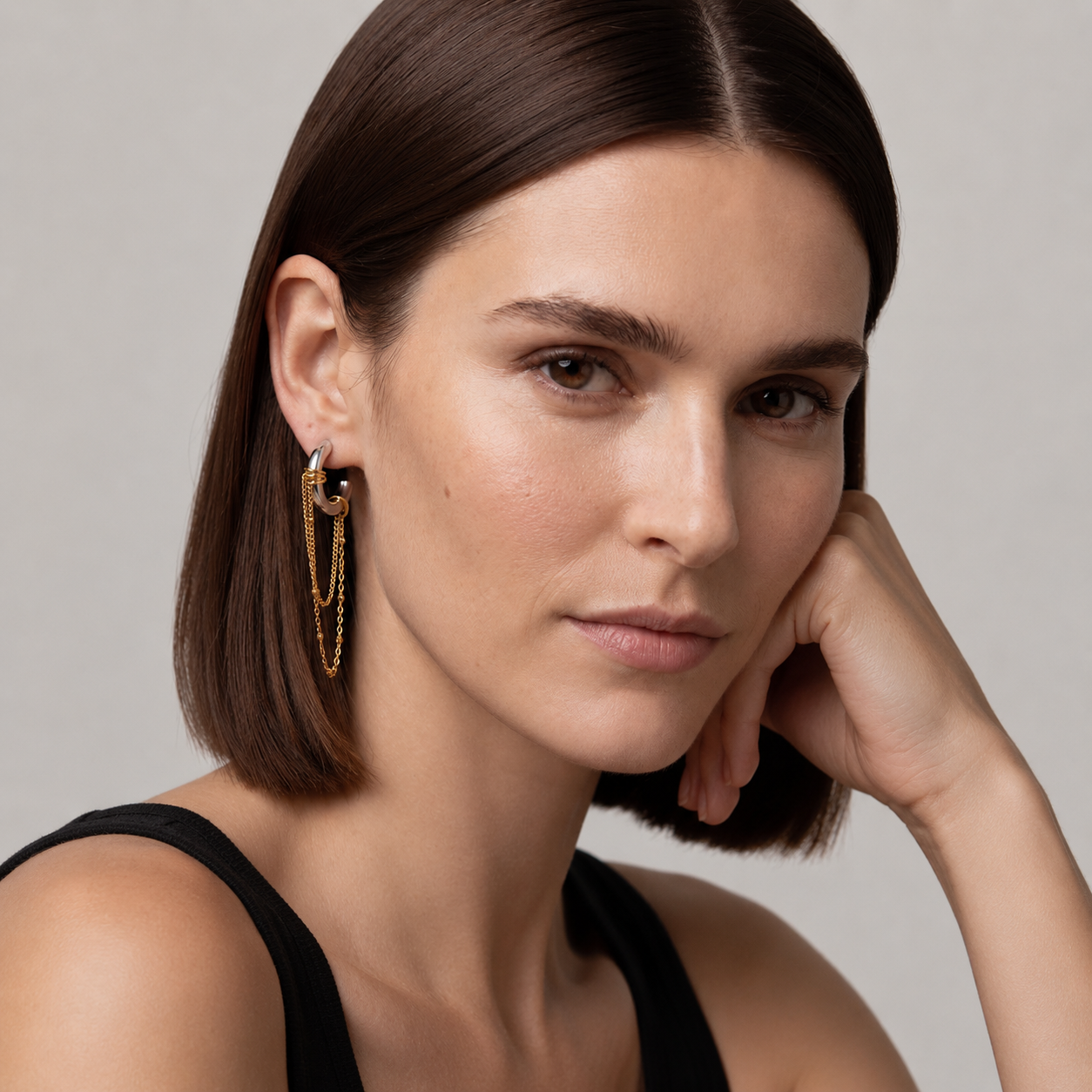 Woman wearing gold hoop earrings with a neutral background