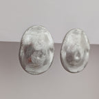 Pair of silver oval earrings on a gradient gray background