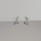 Pair of silver earrings on a gray surface with a light gray background