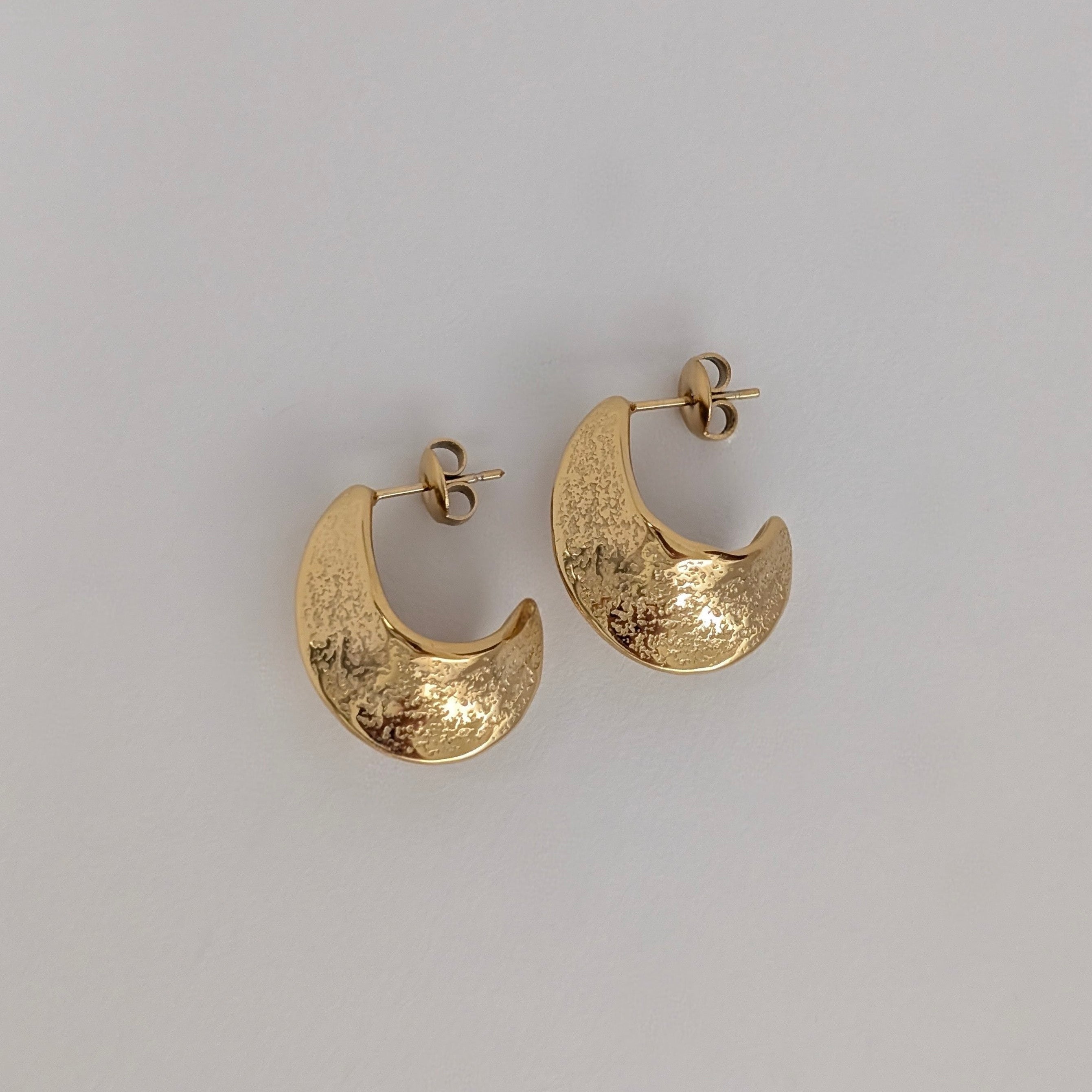 Gold hoop earrings on a light gray background