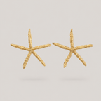 Gold starfish-shaped earrings on a light gray background