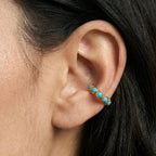 Close-up of an ear wearing a gold earring with turquoise stones