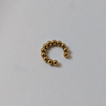 Flat‑lay of Fitta Mini gold ear cuff, waterproof and tarnish‑resistant, on white backdrop.
