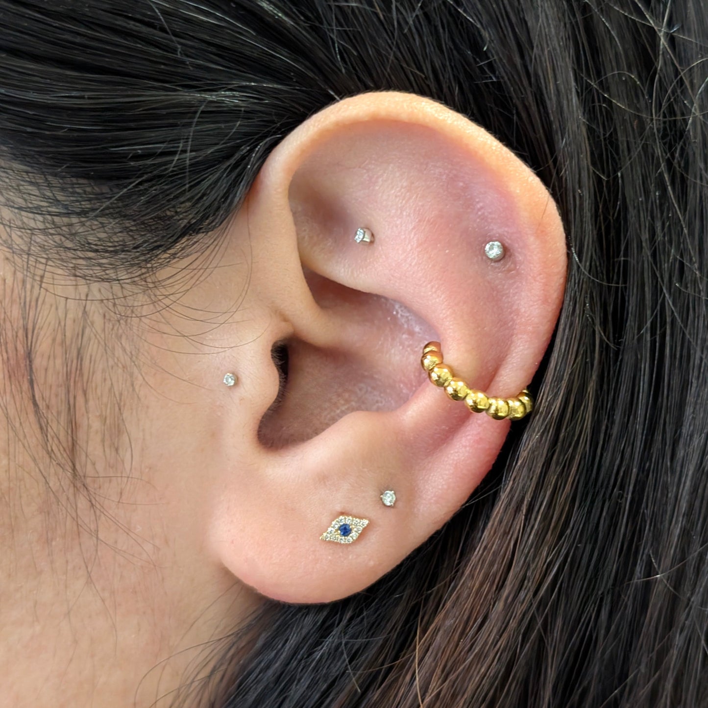 Close‑up of De Mani gold beaded mini ear cuff styled on helix—no piercing needed.