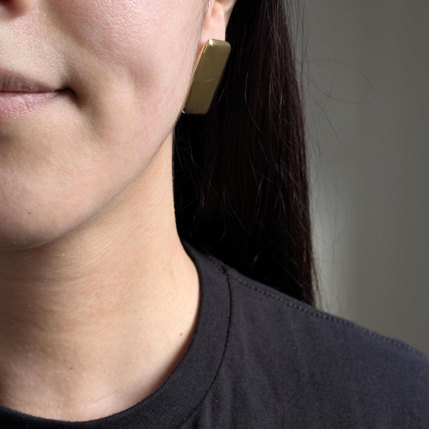 Side on‑ear view showing statement sparkle of gold chunky rectangle studs.