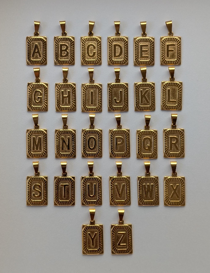 Flat‑lay of all gold medallion letter necklaces A‑Z—18k‑plated initial pendants on rope chains, ready for personalization.