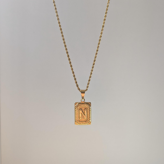 Alternate front angle showing intricate border on personalized gold letter medallion pendant.