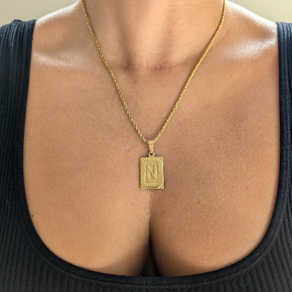 Lifestyle shot: gold medallion letter necklace worn at 20 in length, perfect for everyday layering.