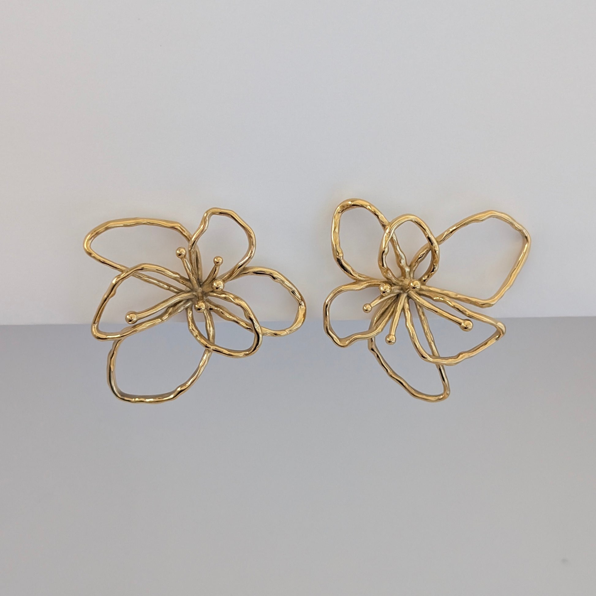 Front view of gold orchid statement earrings—18k plated, 4 × 4.21 cm sculptural floral studs.