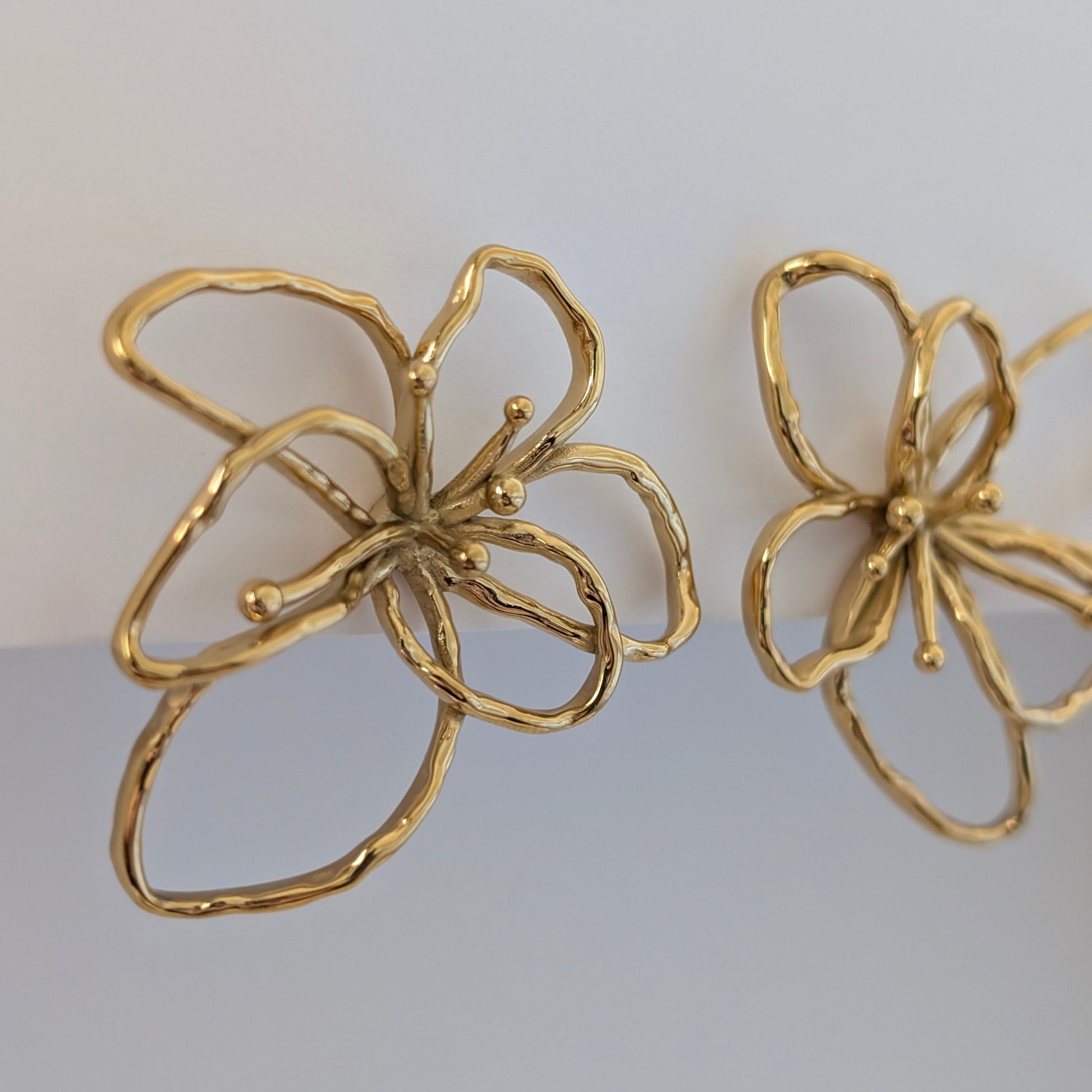 Side view of gold orchid statement earrings—18k plated petals curve outward, lightweight 4 × 4.21 cm floral studs.