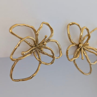 Side view of gold orchid statement earrings—18k plated petals curve outward, lightweight 4 × 4.21 cm floral studs.