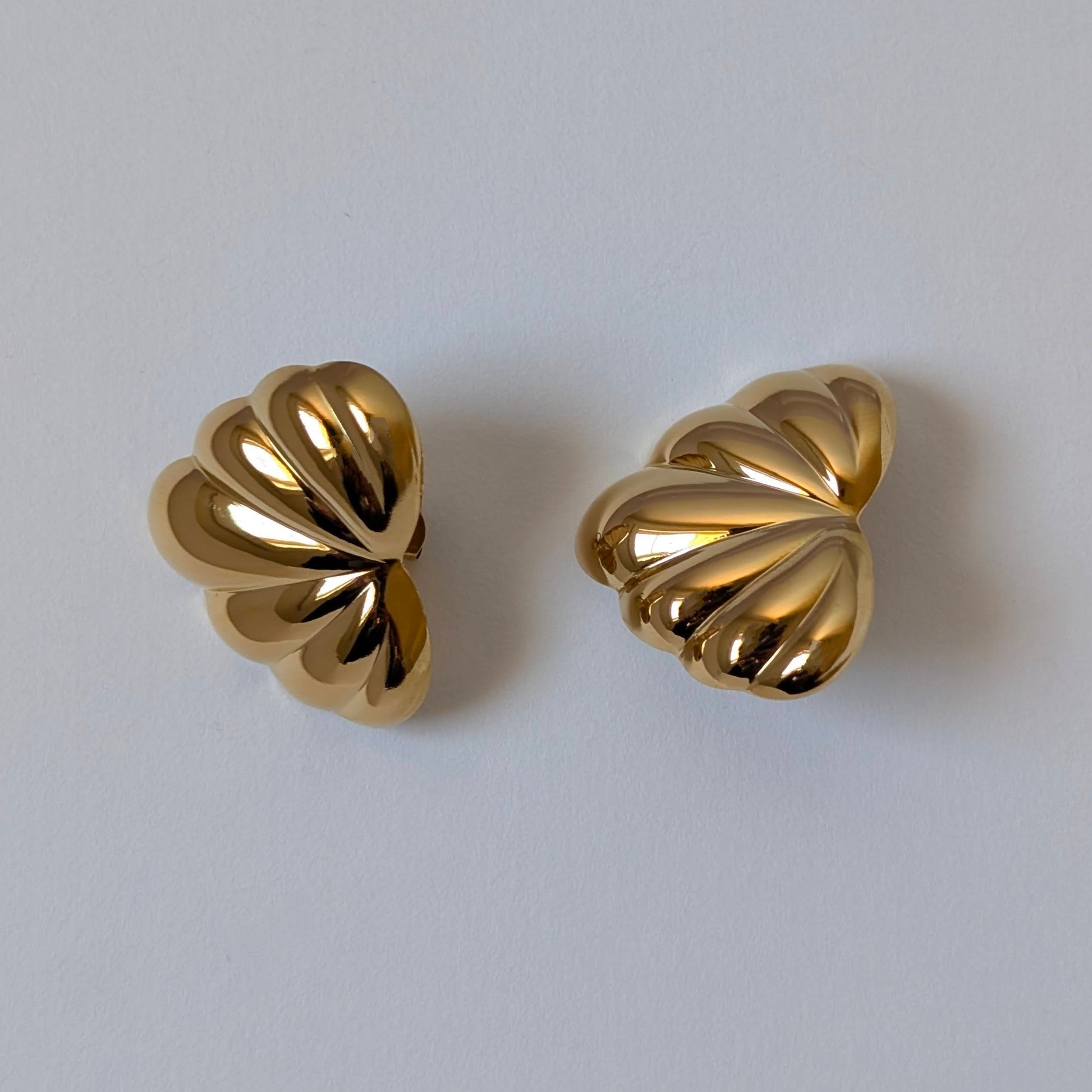 Flat‑lay of Amore gold palm leaf earrings, waterproof PVD coating, tarnish resistant.