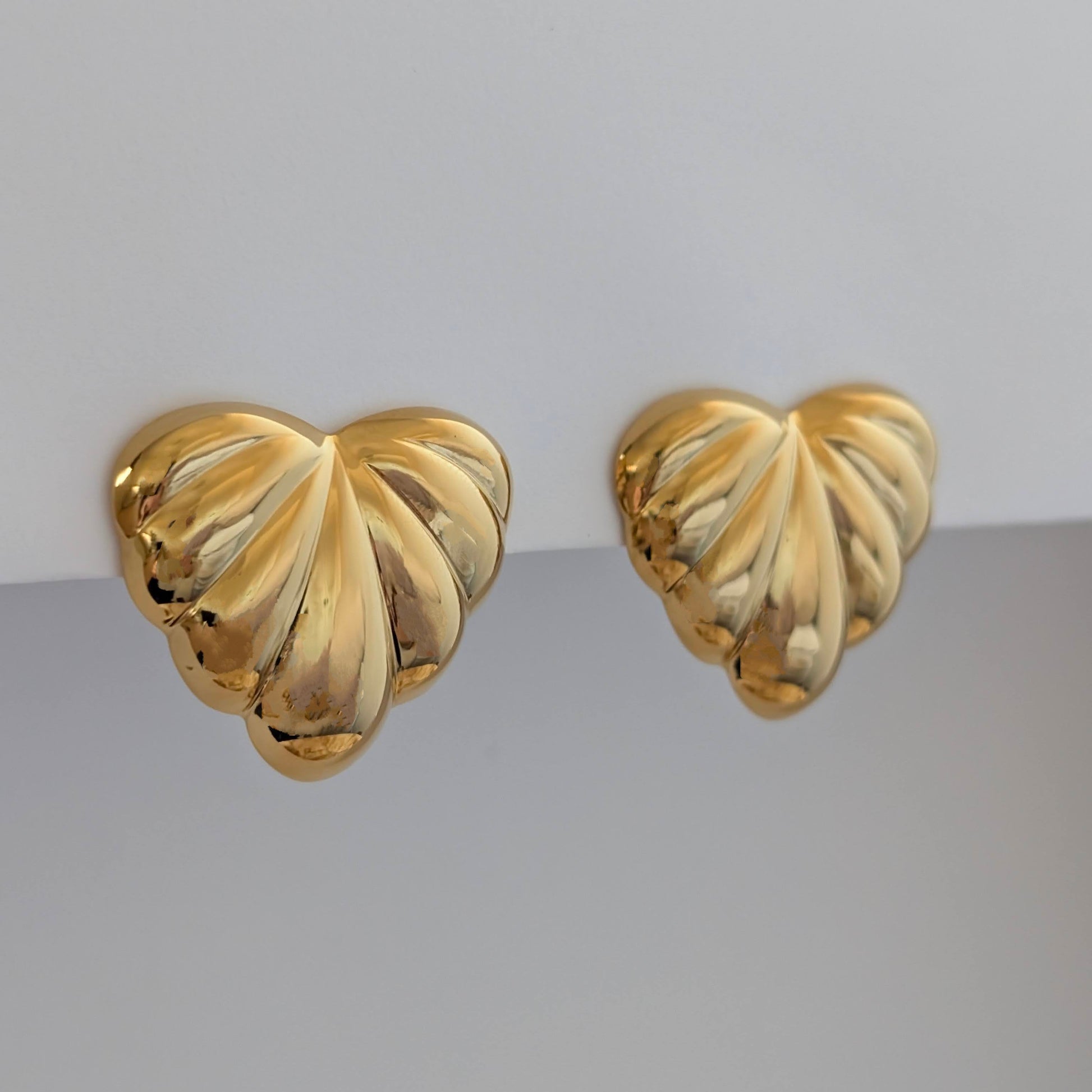Side angle showing sculpted palm leaves and 2.6 × 3 cm size on gold statement earrings.