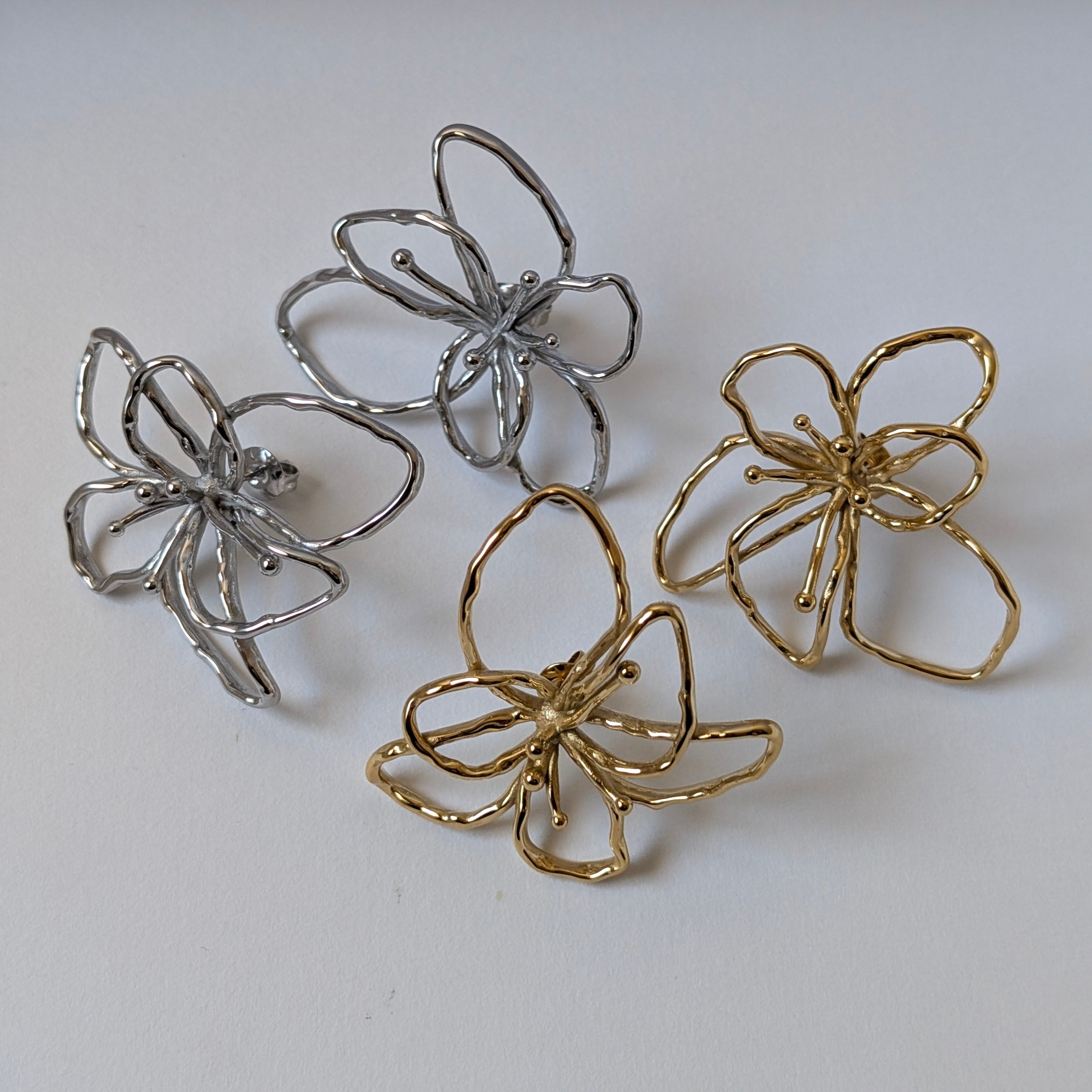 Front‑view comparison of gold and silver orchid statement earrings side‑by‑side for colour choice.