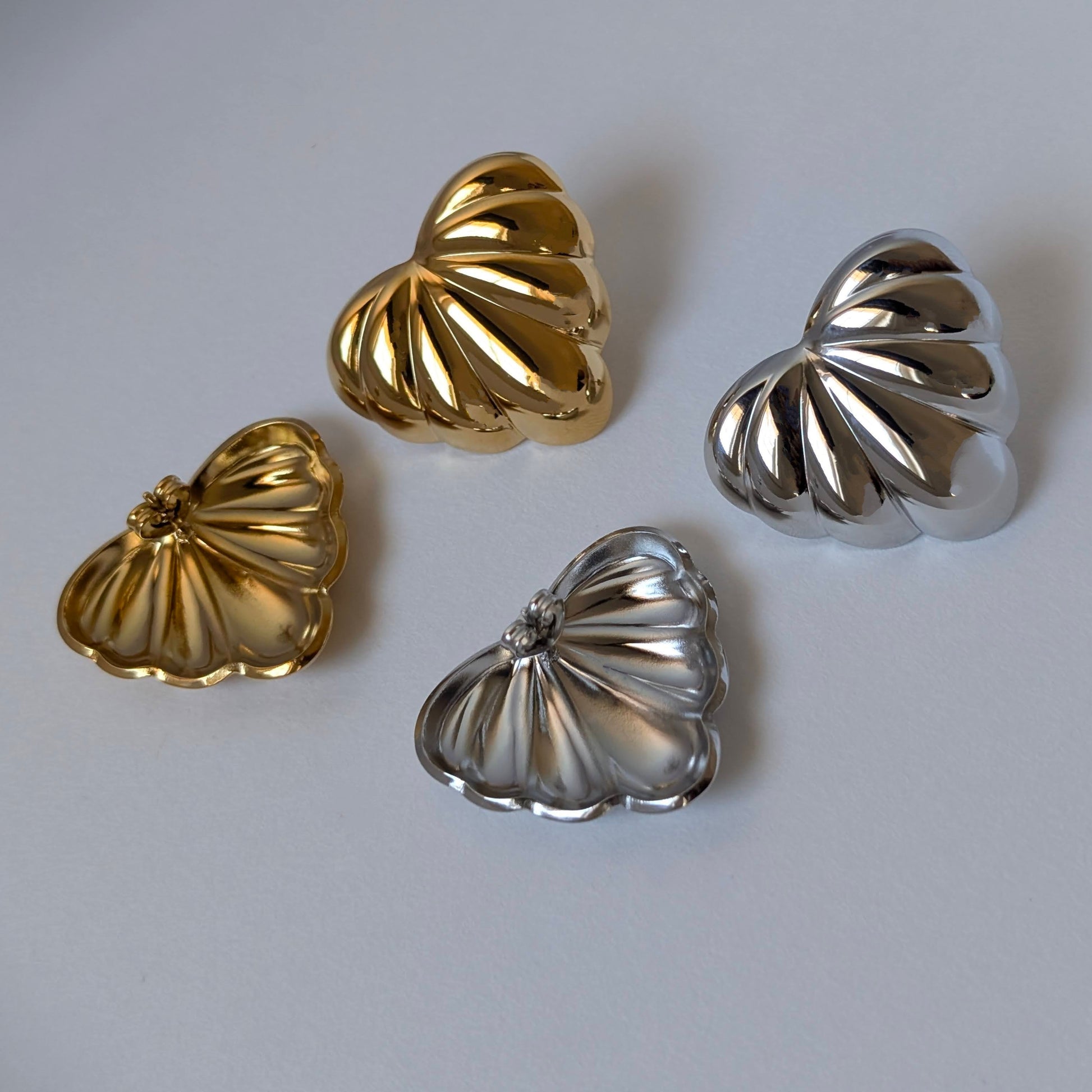 Gold and silver palm leaf statement earrings side‑by‑side—Amore collection, 18k gold‑plated and stainless‑steel.