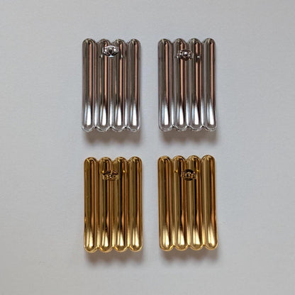 Reverse‑side comparison of gold and silver sculptural stud earrings, showing polished backs and stainless‑steel butterfly clasps.