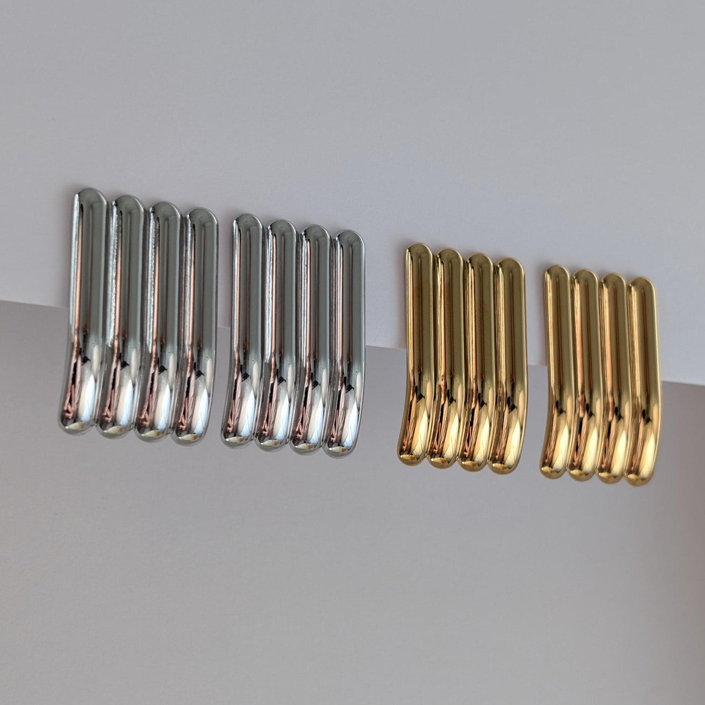 Side view of gold and silver sculptural stud earrings showing curved profile, 3.8 cm drop and hypoallergenic posts.