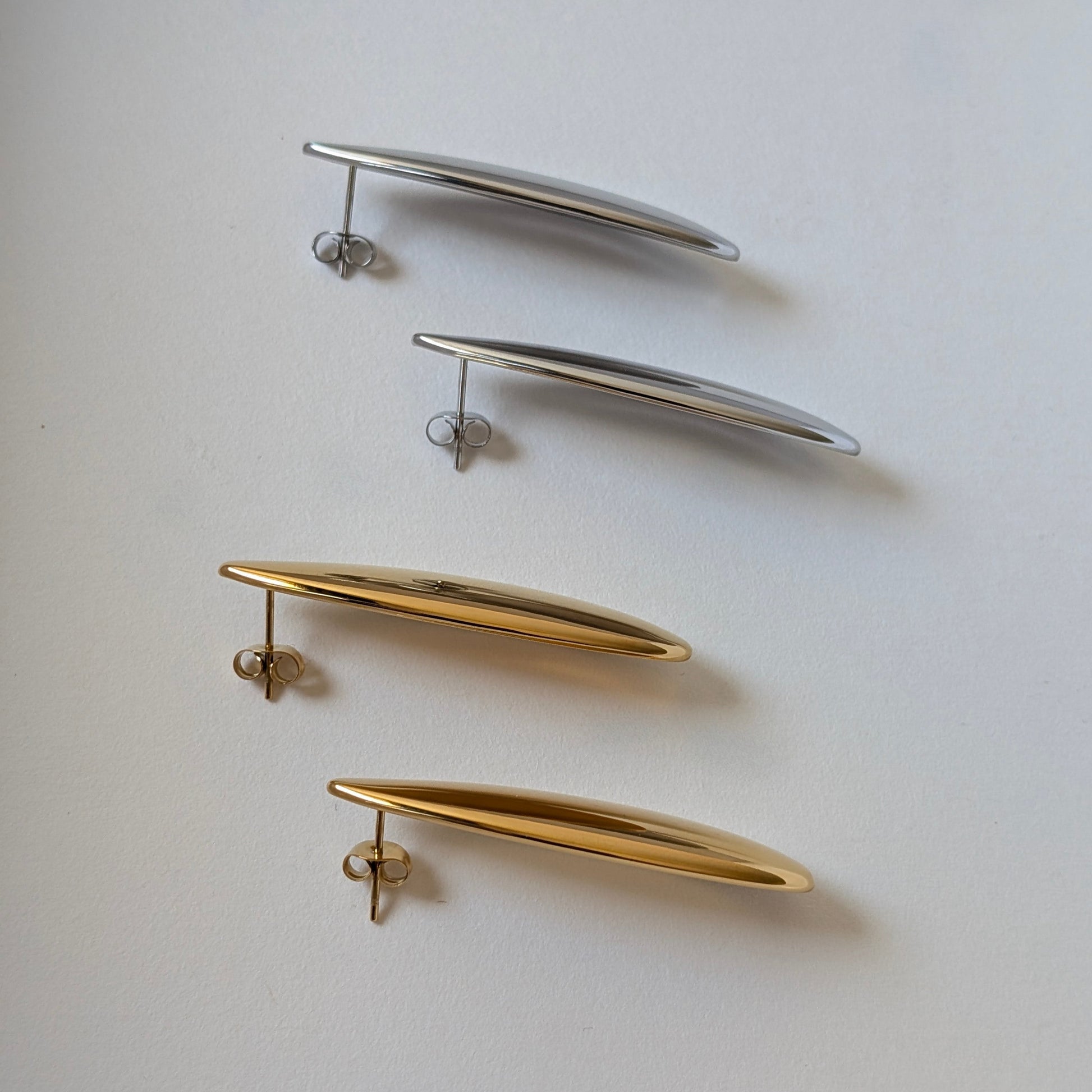 Side‑angle comparison of gold and silver teardrop statement earrings—Raya collection, 4.53 cm drop, high‑shine finish.