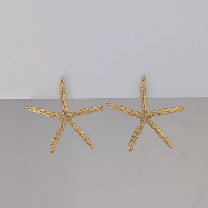 Front view of oversized gold starfish statement earrings—18k plated, polished texture.