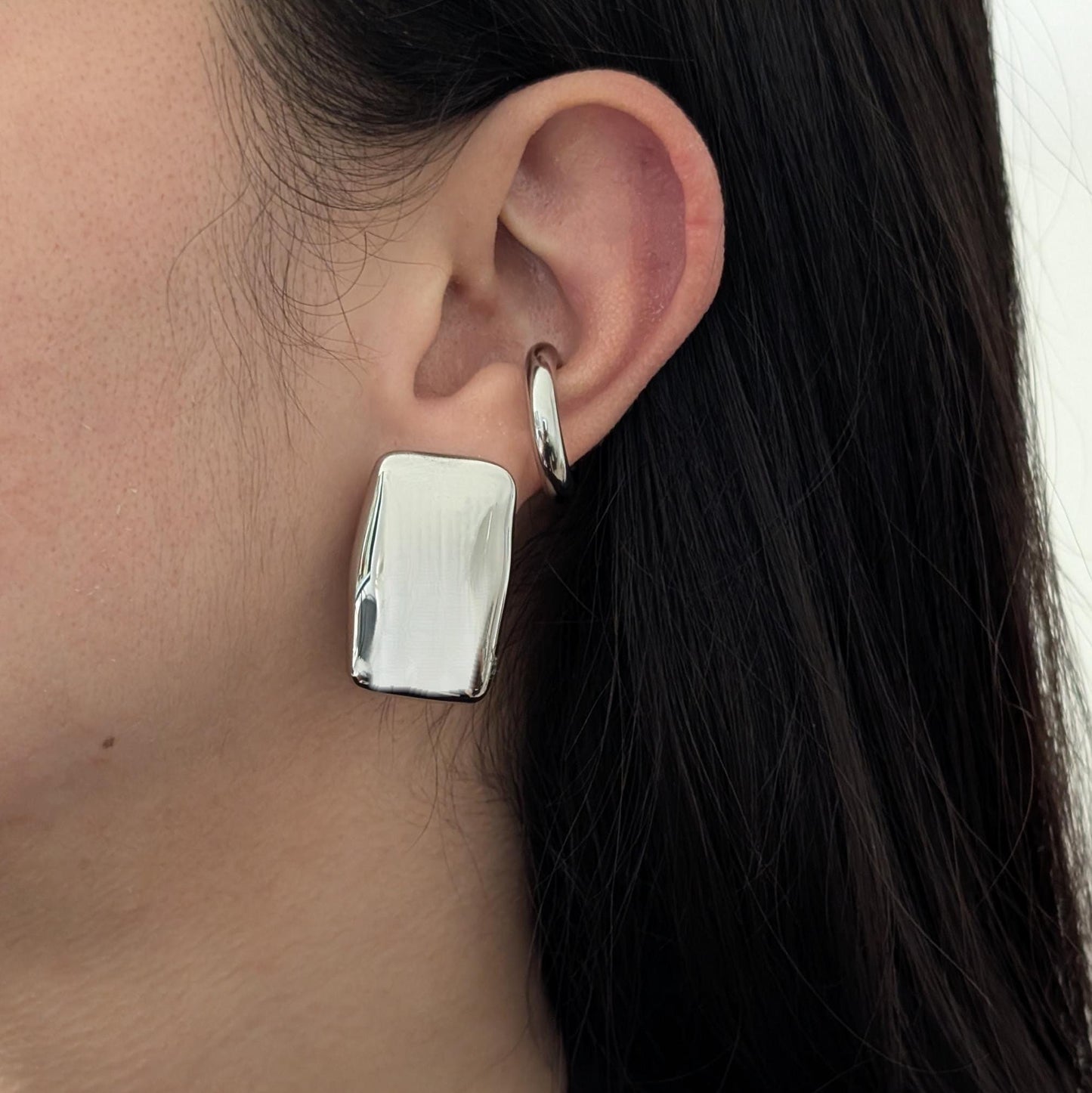Side on‑ear view of silver rectangle studs accenting vintage‑style outfit.