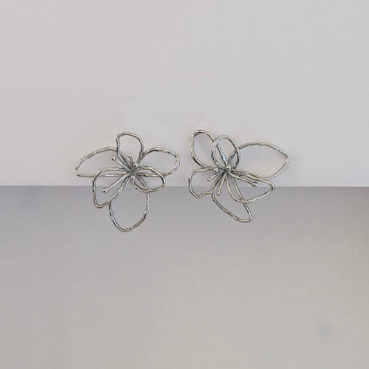 Front view of silver orchid statement earrings—polished stainless steel, sculptural petals, 4 × 4.21 cm studs.