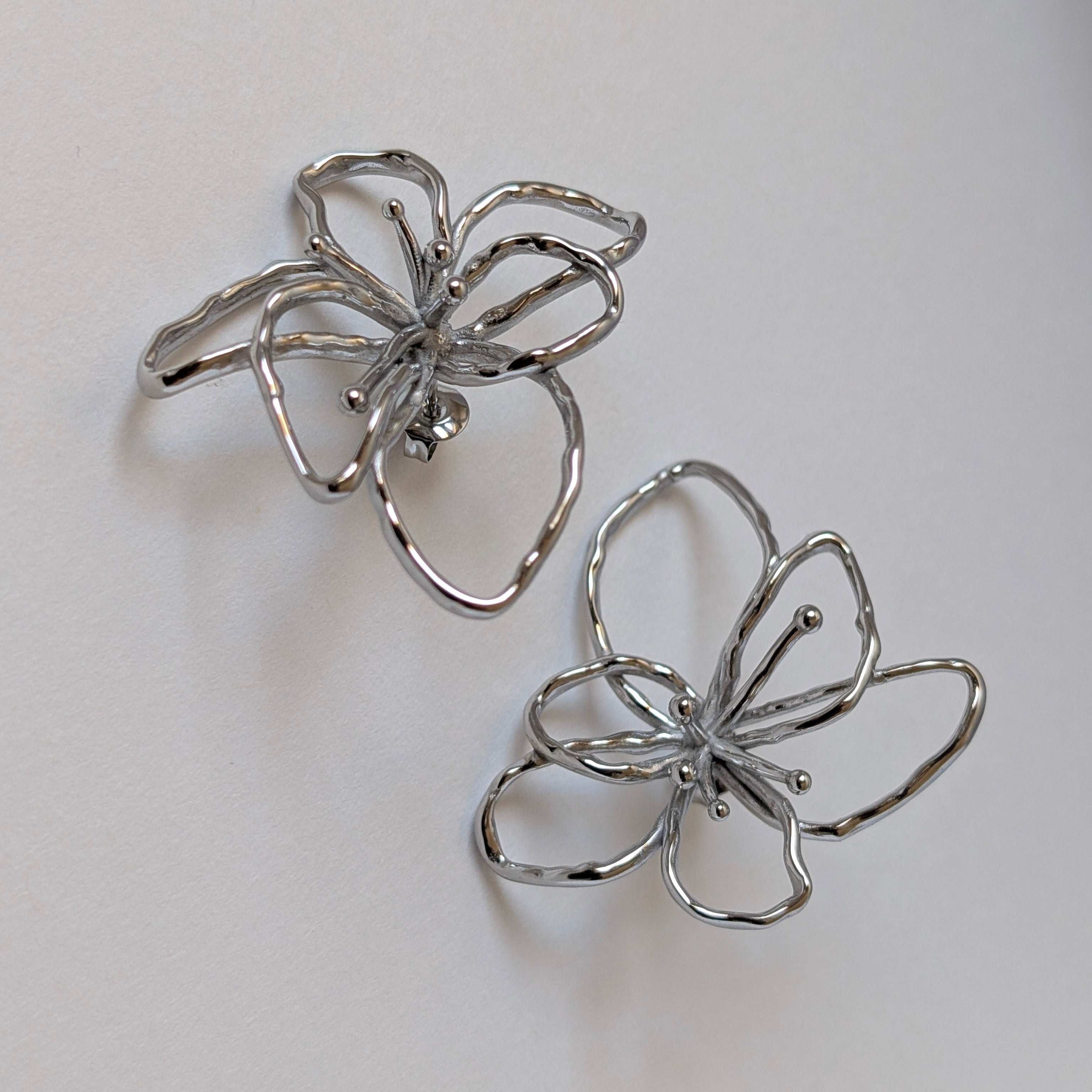 Side view highlighting curved silver orchid petals and hypoallergenic post—waterproof, tarnish‑resistant design.
