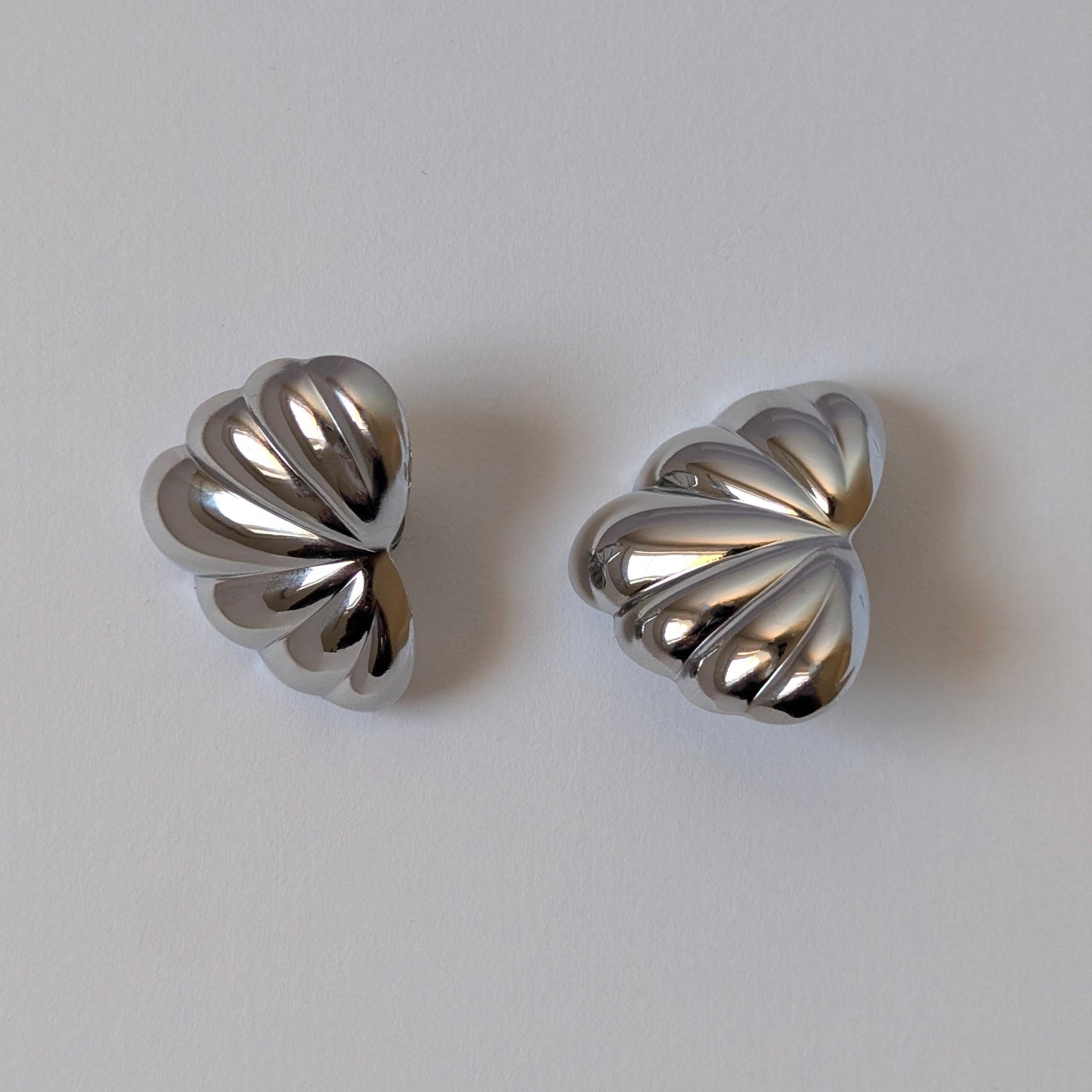 Flat‑lay of silver palm leaf earrings on white background, waterproof PVD plating for daily wear.