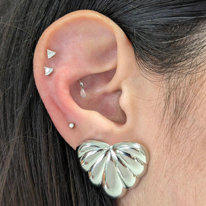 Lifestyle shot of Amore silver palm leaf earrings styled on ear—perfect vacation statement piece.