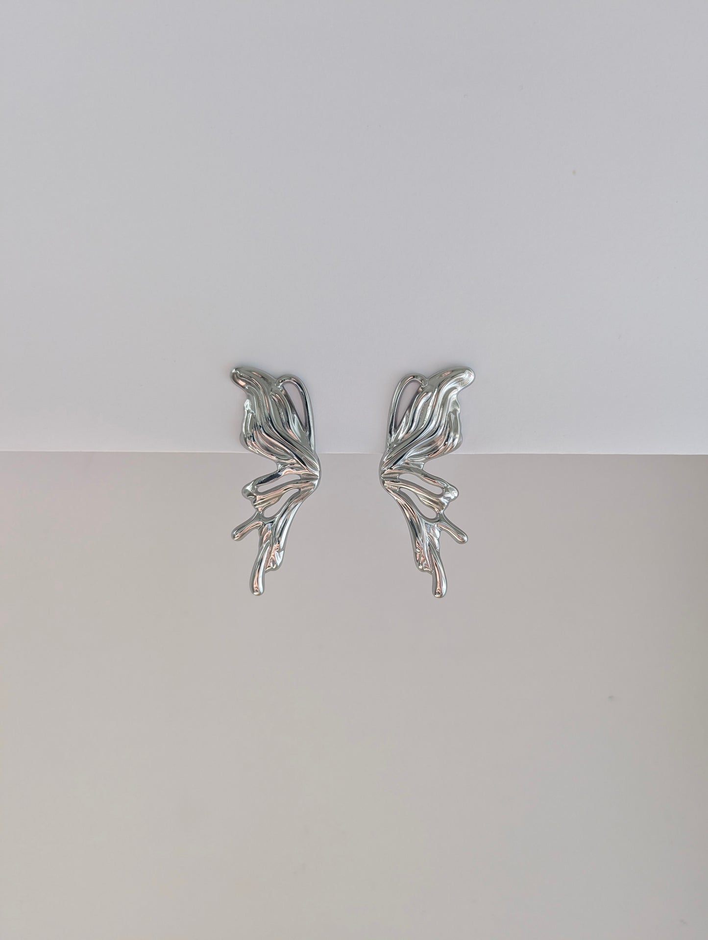 Front view of silver sculptural statement earrings—polished stainless steel, 4.6 × 2.1 cm droplet design.