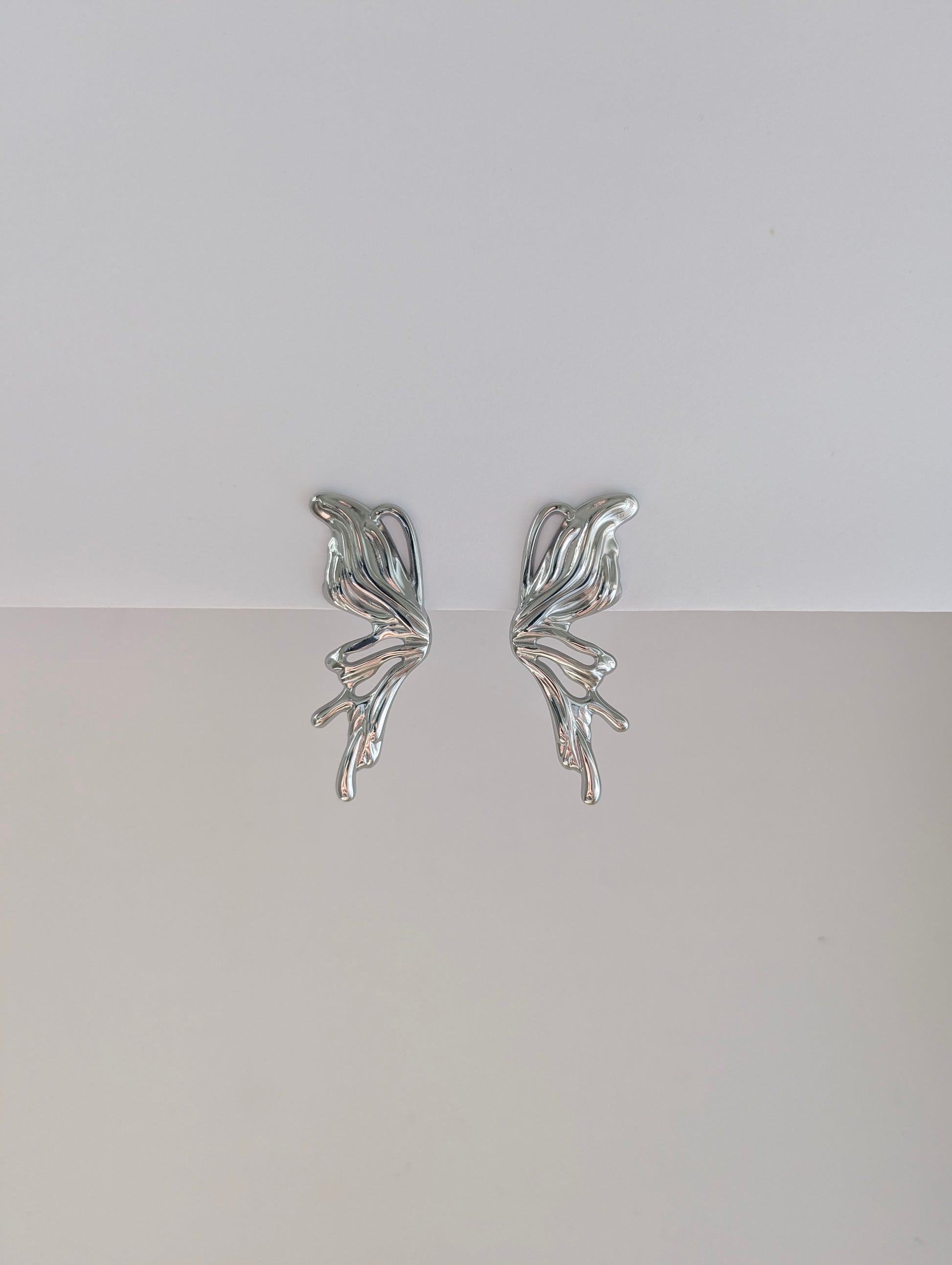 Front view of silver sculptural statement earrings—polished stainless steel, 4.6 × 2.1 cm droplet design.